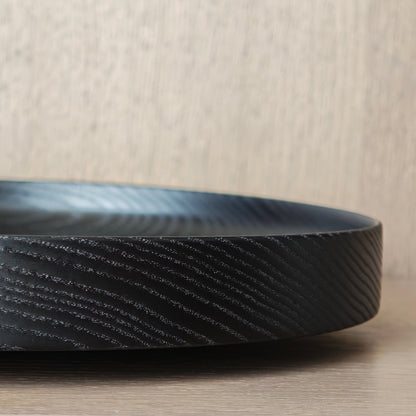 Close-up of a black ash wood platter on a wooden surface