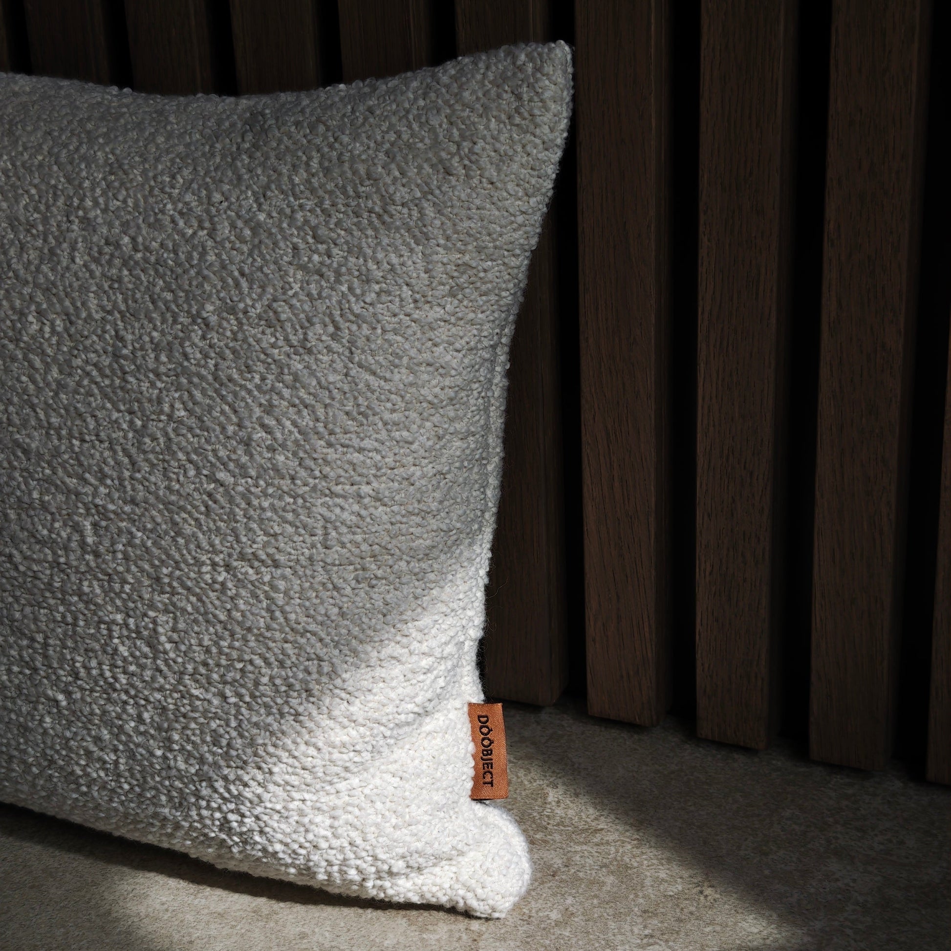 Textured beige pillow with a brand tag on a dark background