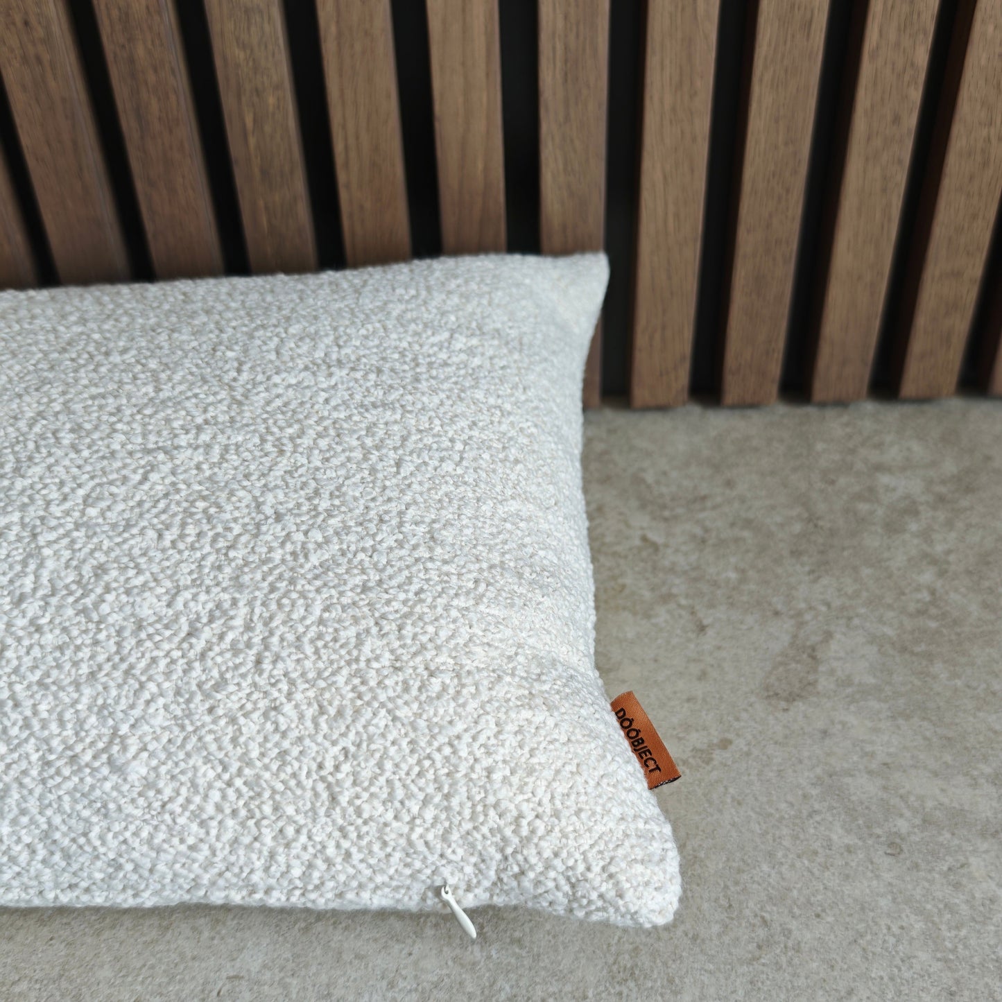 Textured pillow on a concrete surface with a wooden slat background
