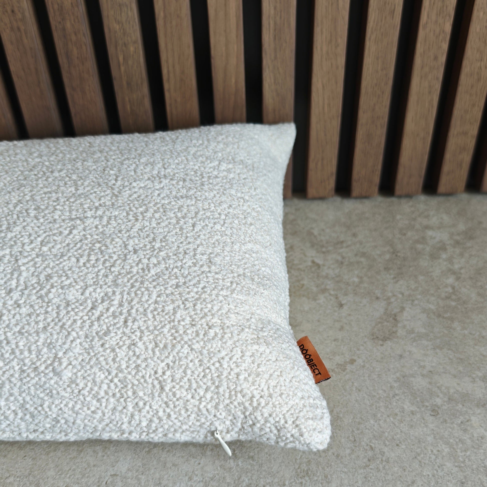 Textured pillow on a concrete surface with a wooden slat background