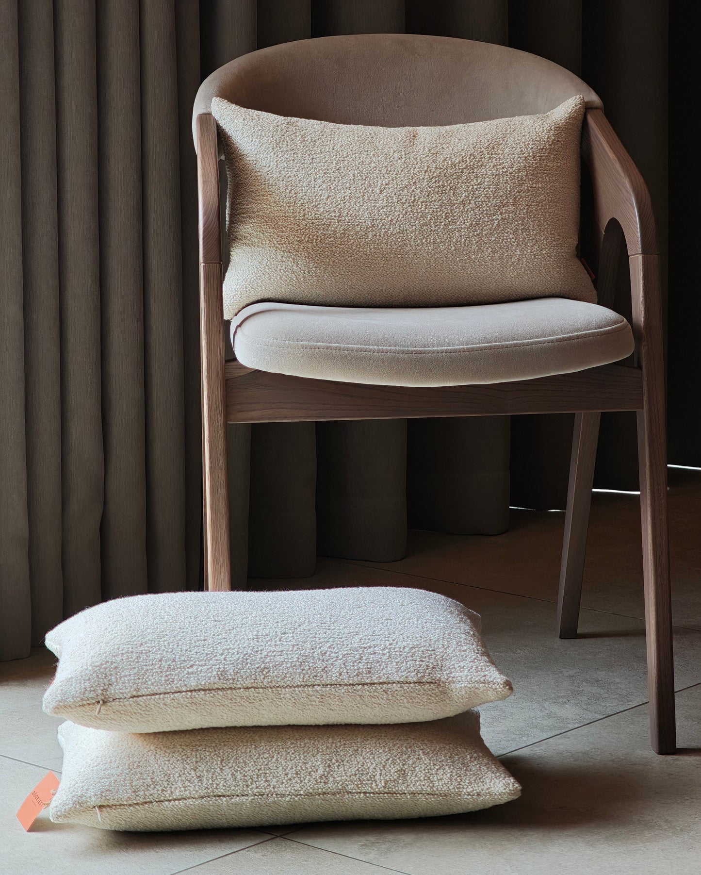 Bouclè off white pillow on the chair and on the tiles floors with curtains background