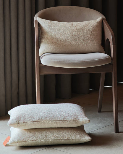 Bouclè off white pillow on the chair and on the tiles floors with curtains background
