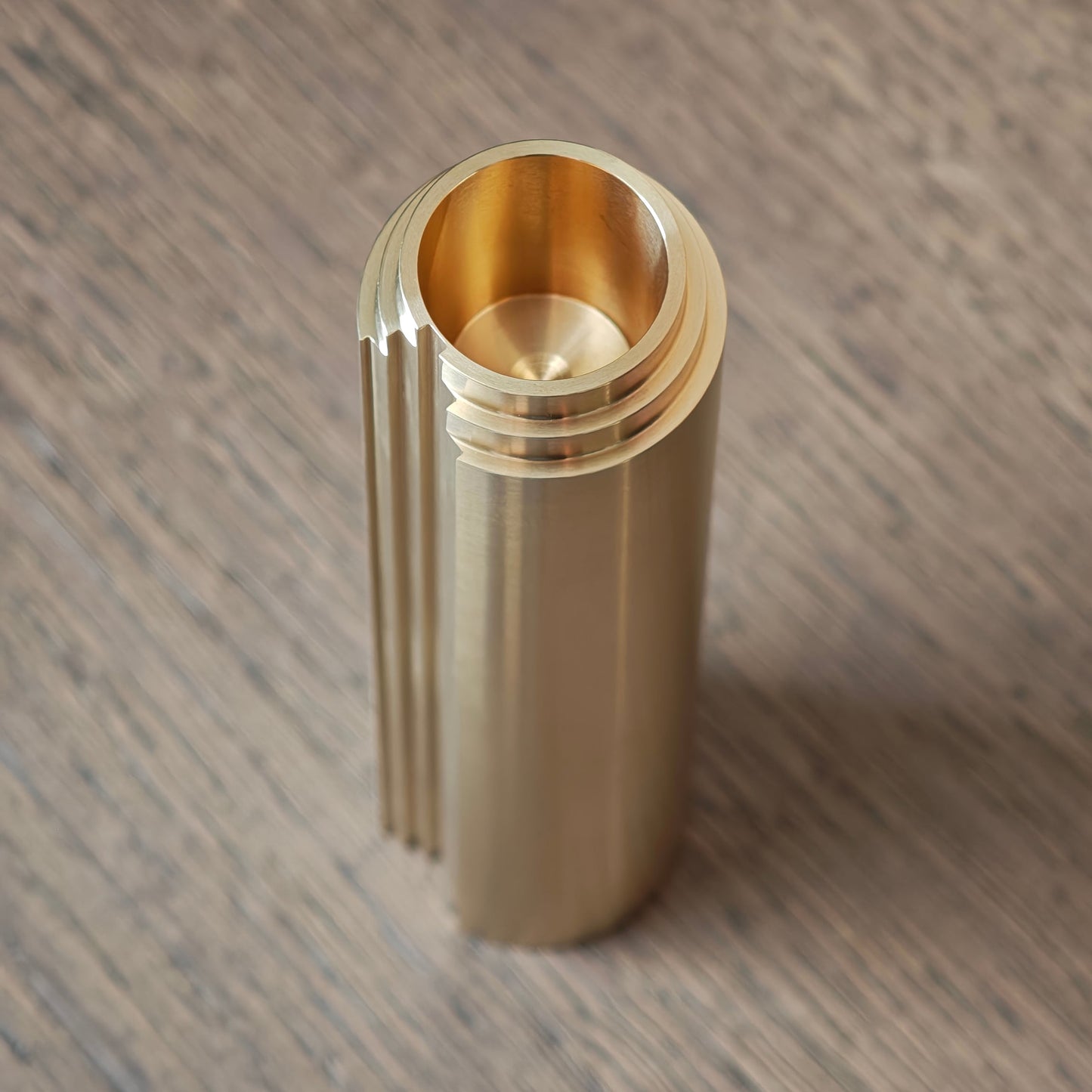 Brass cylindrical object on a wooden surface