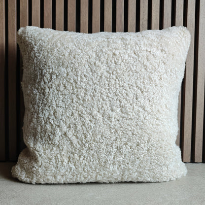 Textured white pillow on a tiles floor with a striped wall background