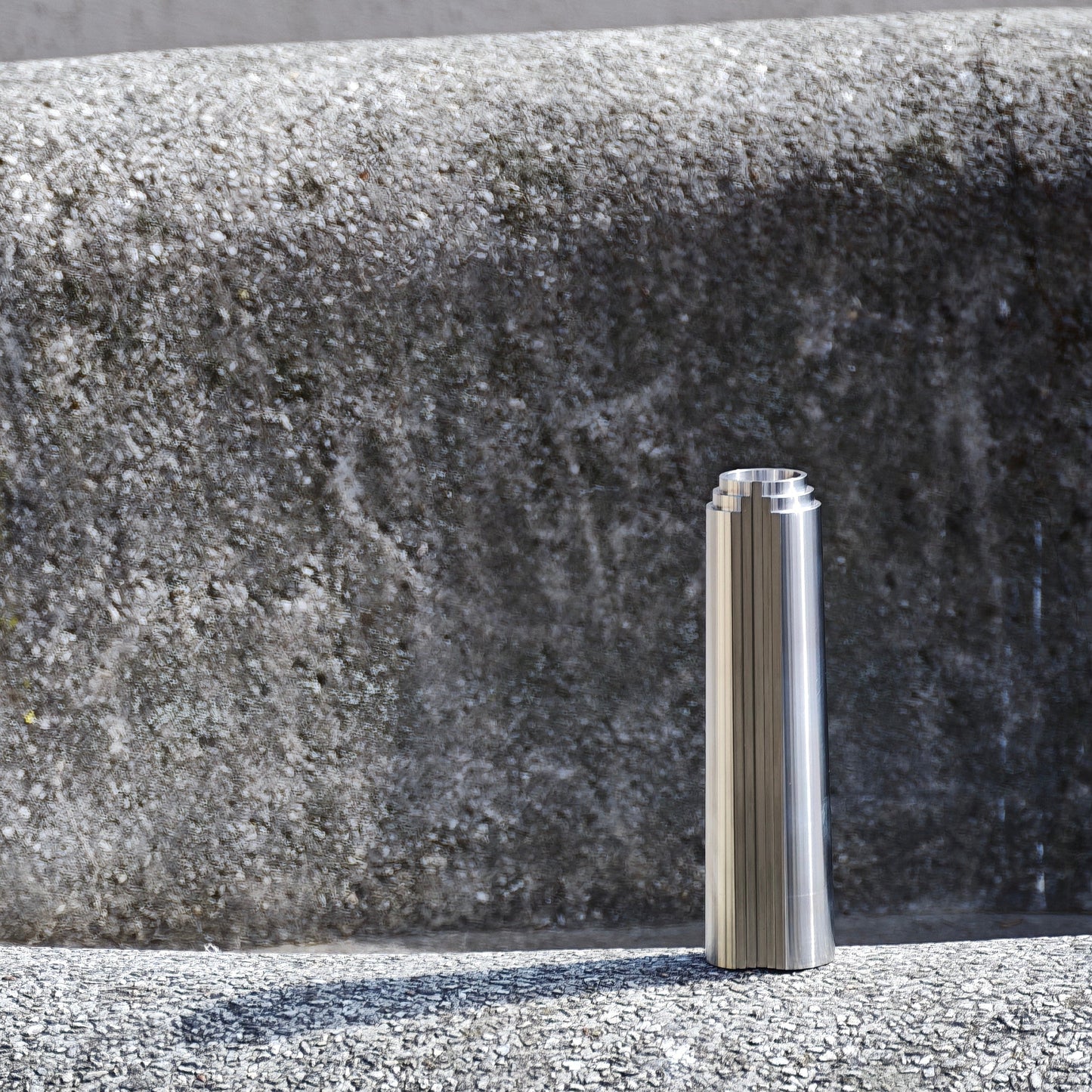 Stainless steel cylindrical object on a textured rounded concrete surface