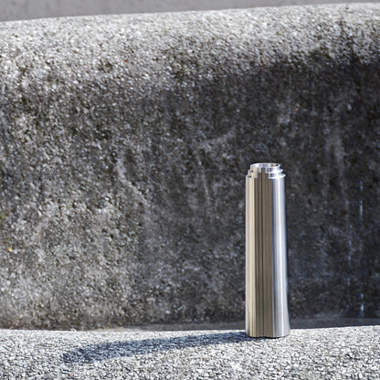 Stainless steel cylindrical object on a textured rounded concrete surface