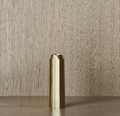 Brass cylindrical object on a wooden surface with a neutral background