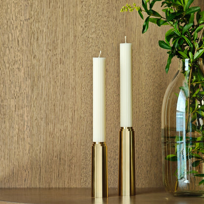 Wooden cabinet with two white candles and a vase with greenery on a neutral background