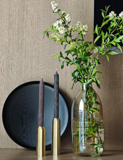 Decorative setting with a vase of flowers, candles, and a plate on a wooden surface.