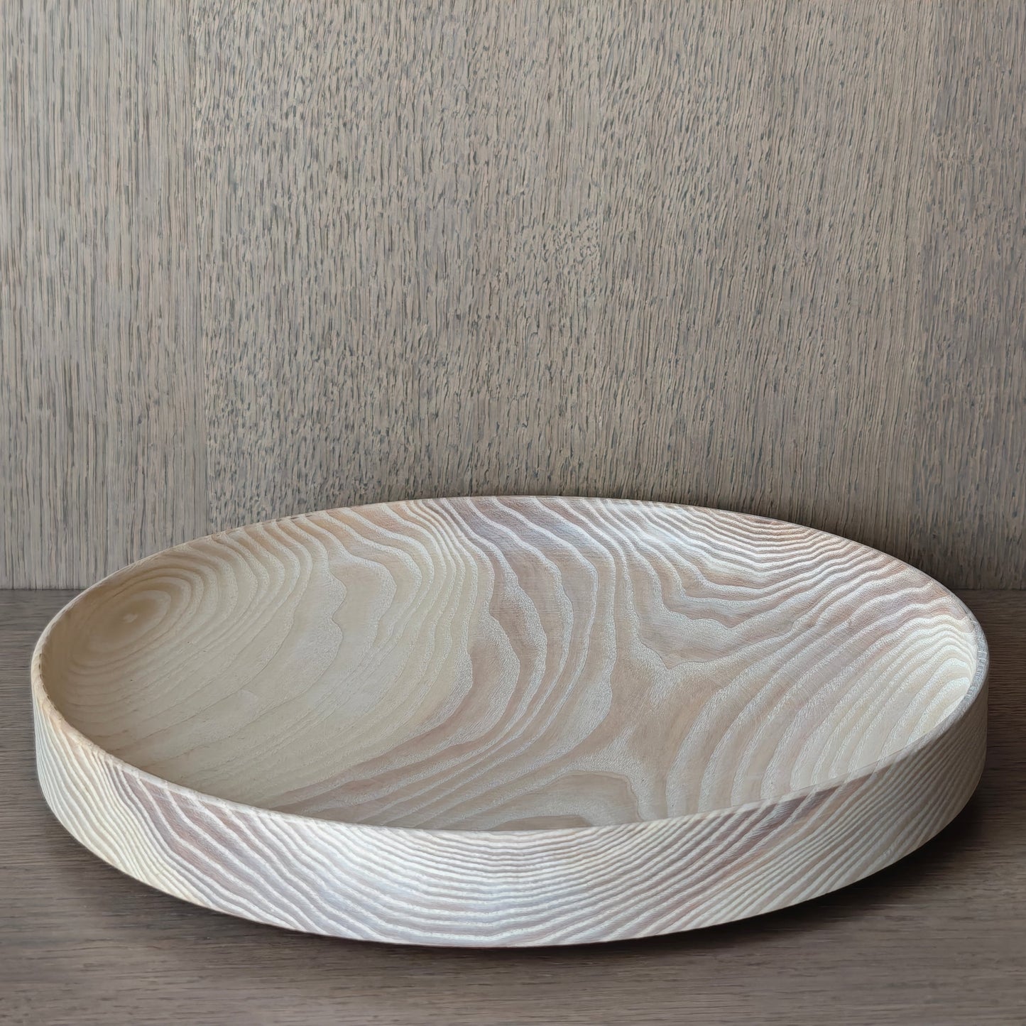 Round off white wooden tray on a wooden surface with a wall panelling background