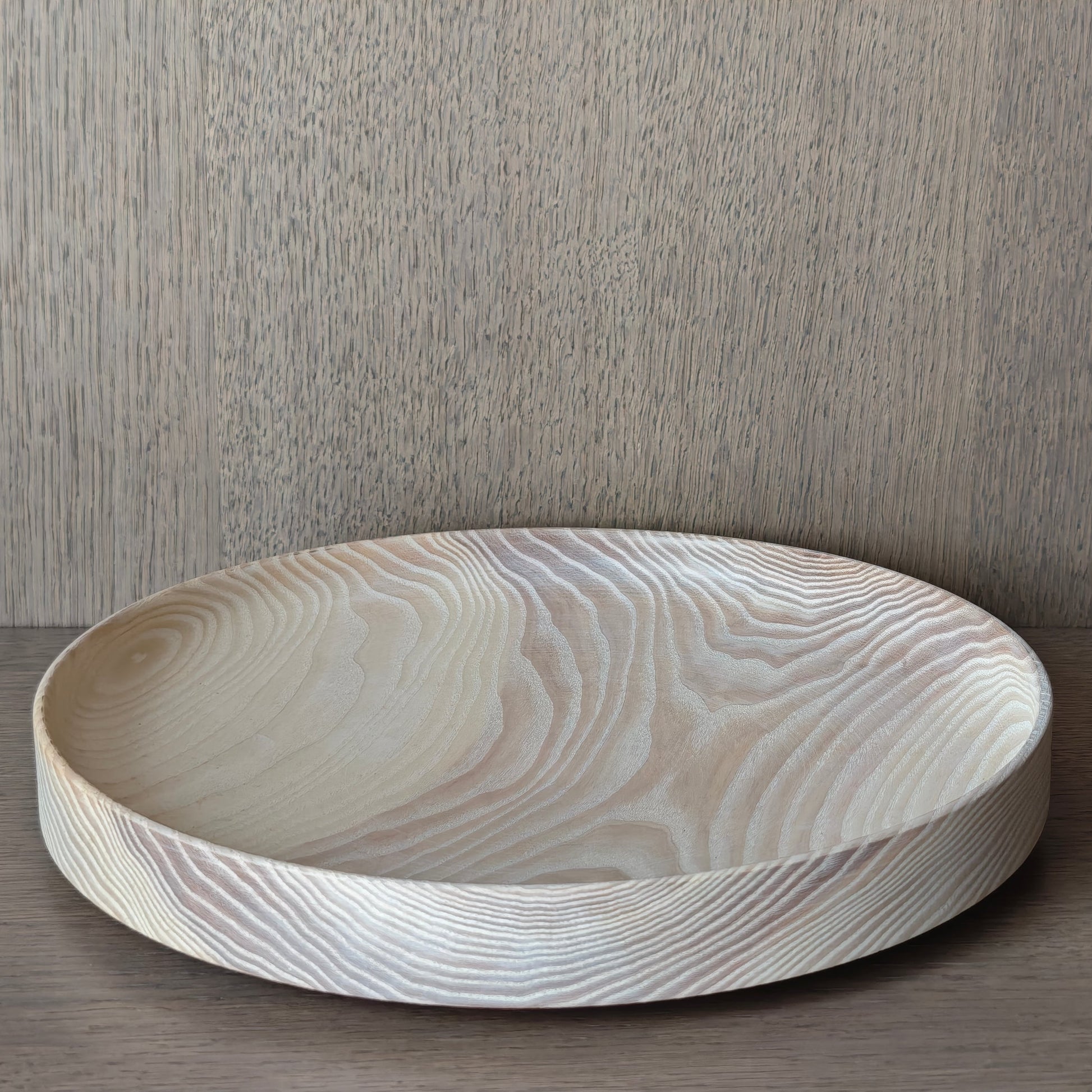 Round off white wooden tray on a wooden surface with a wall panelling background