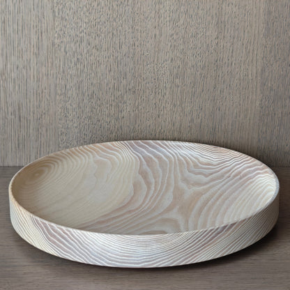 Round off white wooden tray on a wooden surface with a wall panelling background