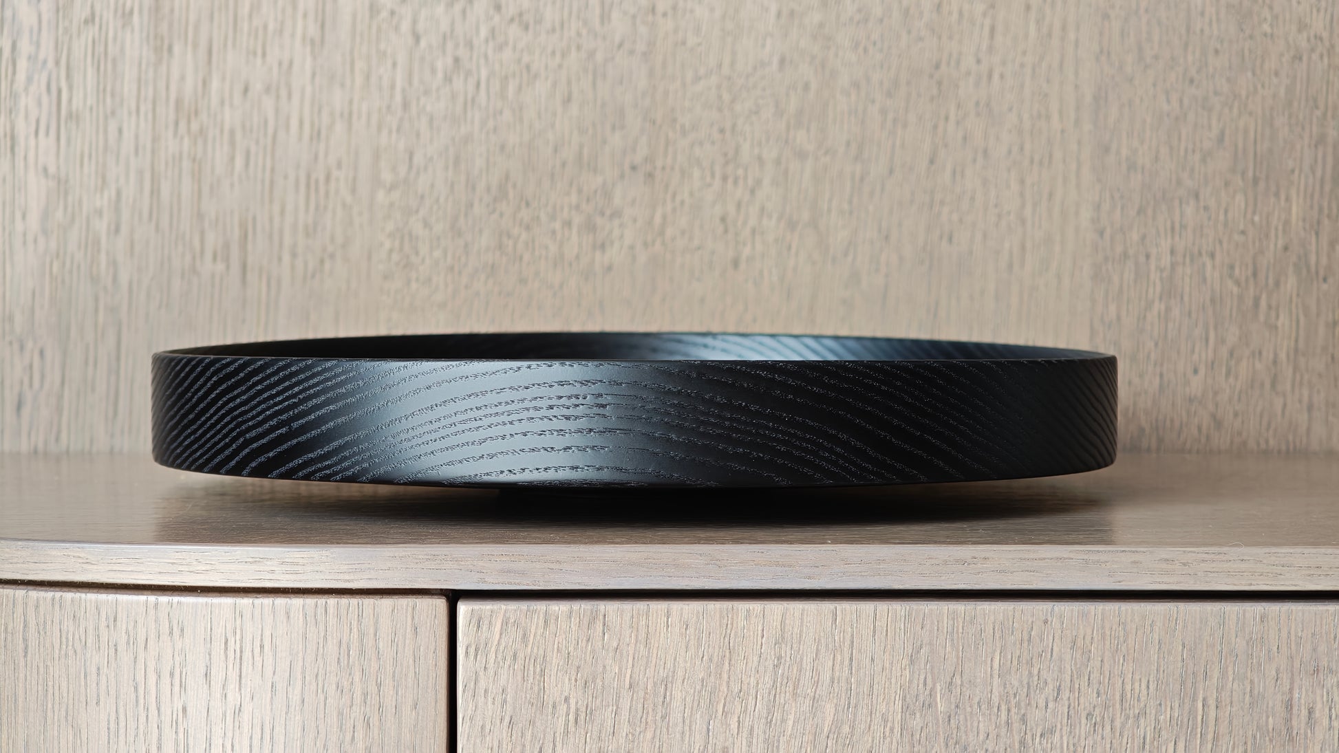 Black decorative wooden plate on a wooden surface with a neutral background