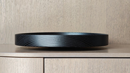 Black decorative wooden plate on a wooden surface with a neutral background