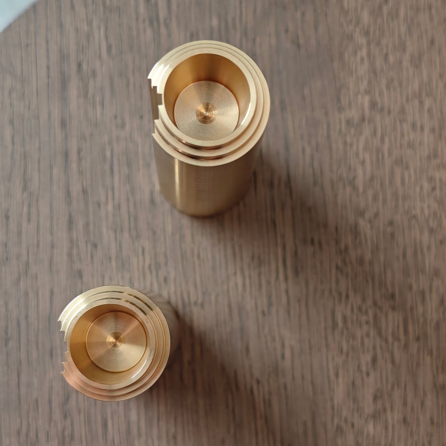 Two brass candle holders on a wooden surface