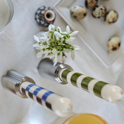 Top-down view of a table setting with candle holders, glasses, a flower arrangement, and white tablecloth.