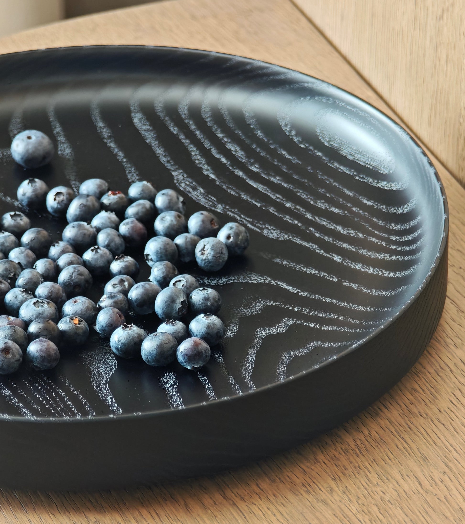 Black wooden plate with blueberries on a wooden surface