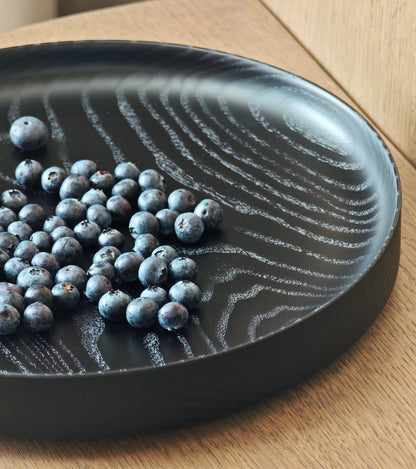 Black wooden plate with blueberries on a wooden surface