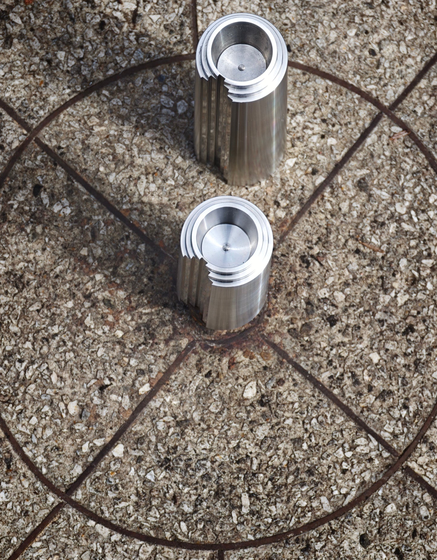Stainless steel candleholders on a terazzo surface